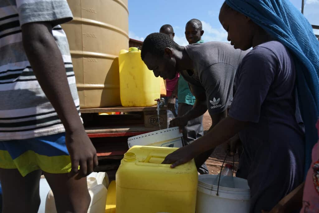 Les habitants du bidonville viennent remplir leurs bidons avec l’eau potable ramenée par la Croix Rouge.