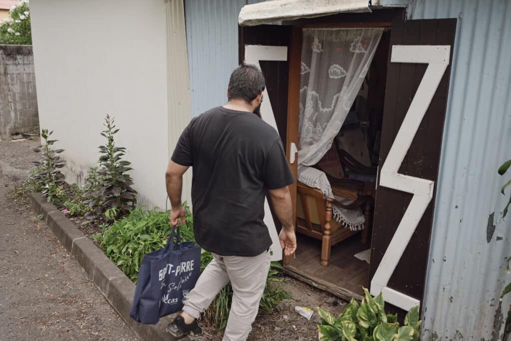 Abdou rend visite à madame Itema chez elle pour lui apporter un panier alimentaire.